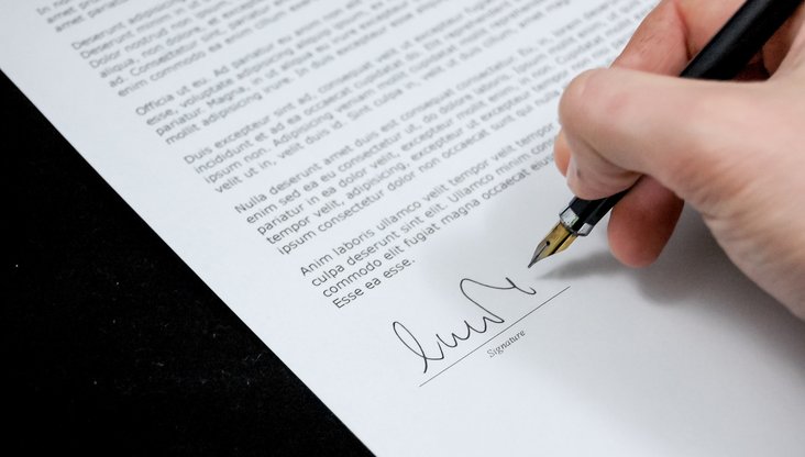 Hand holding a pen ready to sign a document.
